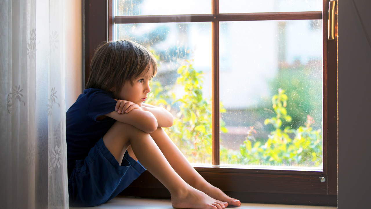Young boy sitting on a window seat, looking outside