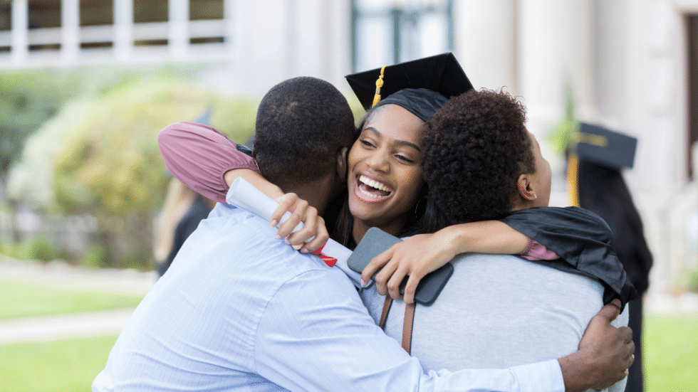 Young woman in graduation cap hugging her parents