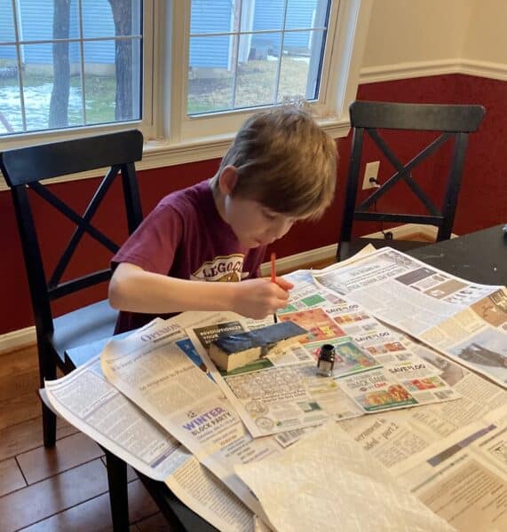Child painting at the kitchen table with newspapers